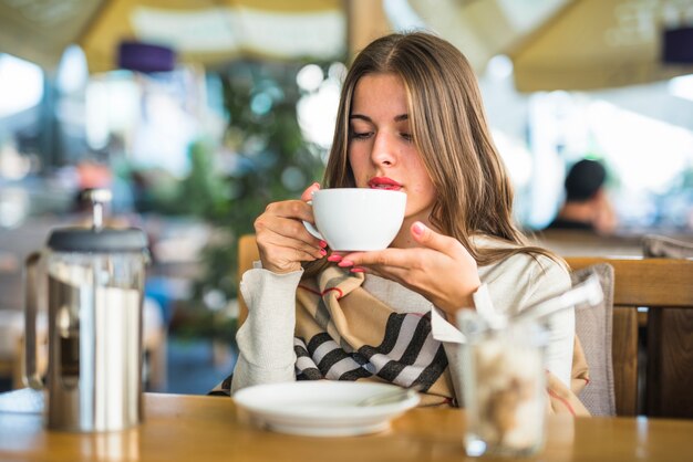 Blonde jeune femme buvant de la tisane en tasse blanche