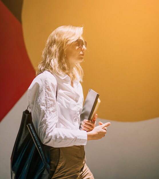 Blonde jeune femme marchant avec des journaux intimes à la main