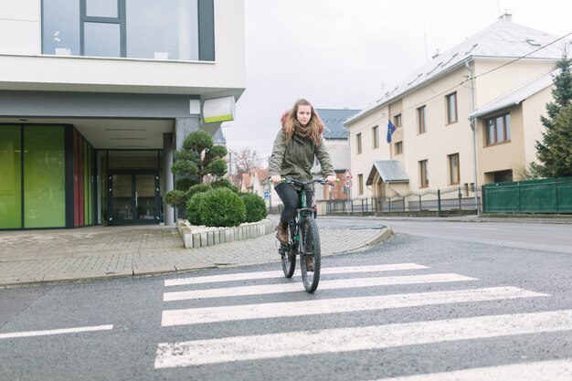 Blonde jeune femme portant un vélo à capuche en ville