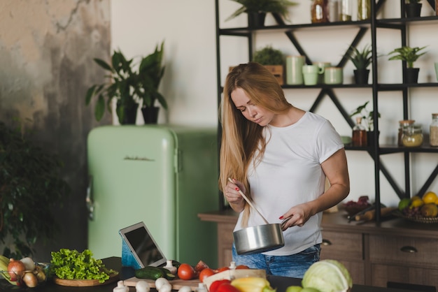 Blonde jeune femme préparant la nourriture dans la cuisine