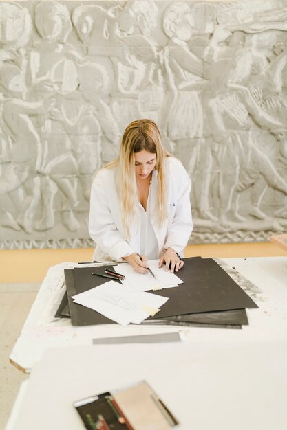 Blonde jeune femme s&#39;appuyant sur du papier blanc au-dessus de la table