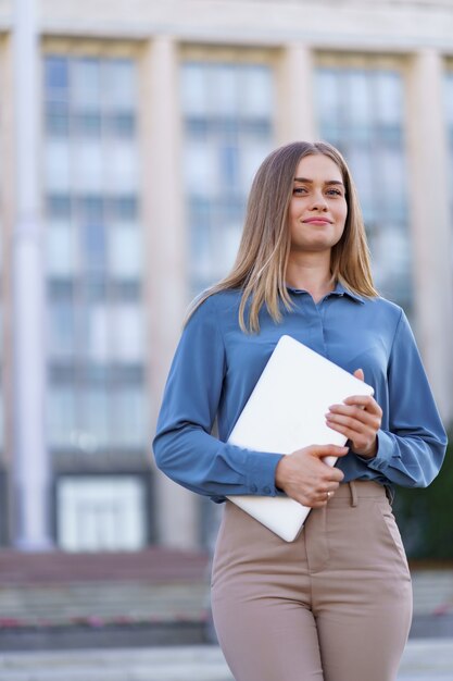 Blonde jeune femme souriante portrait portant une chemise douce bleue sur le bâtiment