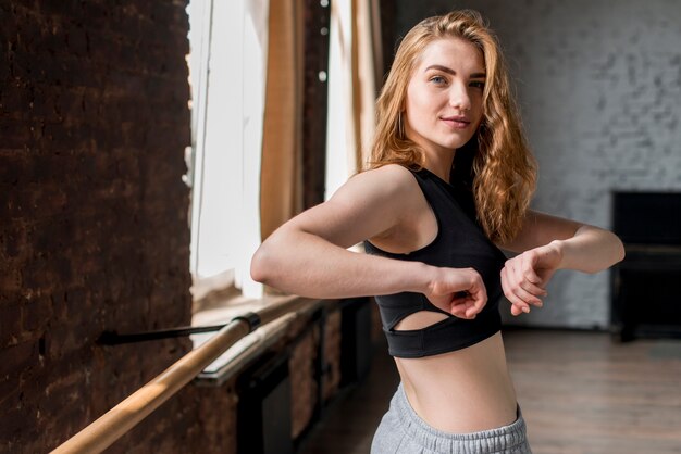 Blonde jeune femme en vêtements de fitness exerçant en studio de danse