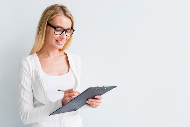 Blonde avec des lunettes écrit sur le presse-papiers