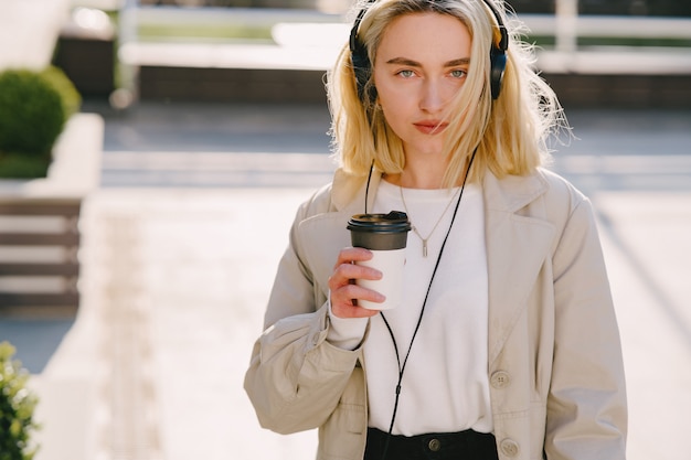 Blonde se promène dans la ville d'été avec une tasse de café