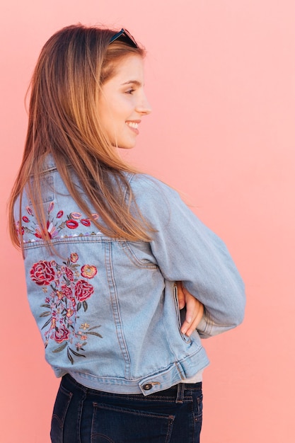 Blonde souriante jeune femme avec ses bras croisés sur fond rose