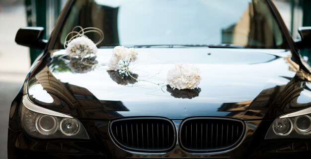 BMW noire décorée de bouquets de mariage blancs