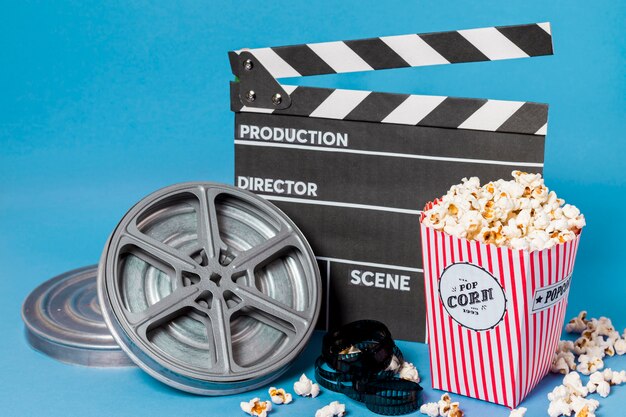 Bobines de film; bandes de film et clap avec boîte de pop-corn sur fond bleu