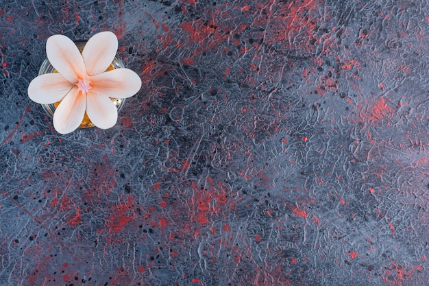 Un bocal en verre avec une belle fleur rose sur marbre