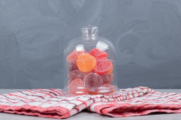 Photo gratuite un bocal en verre de bonbons sucrés sur une nappe rouge.