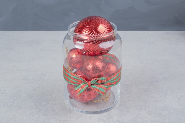 Un bocal en verre de boules de Noël rouges sur fond sombre. Photo de haute qualité
