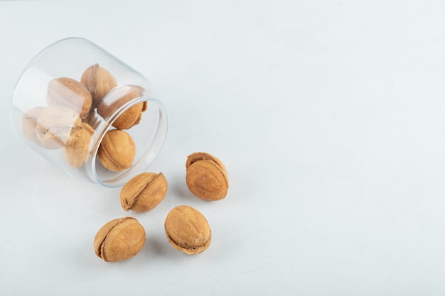 Photo gratuite un bocal en verre rempli de biscuits sucrés en forme de noix.