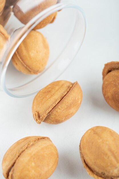 Un bocal en verre rempli de biscuits sucrés en forme de noix.