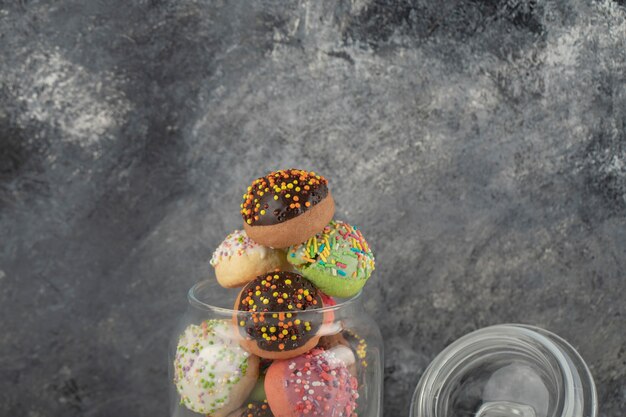 Un Bocal En Verre Rempli De Petits Beignets Colorés.