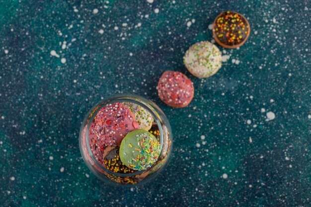 Un bocal en verre rempli de petits beignets colorés.