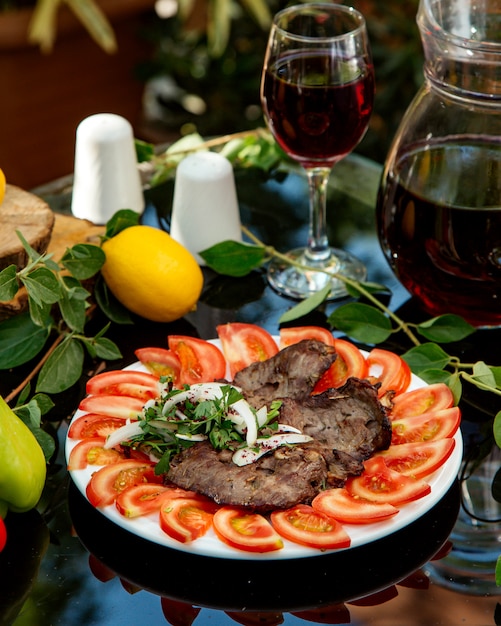 Photo gratuite boeuf mariné servi avec tranches de tomate, oignon et coriandre