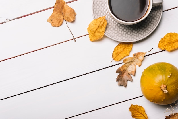 Photo gratuite boisson chaude près des feuilles et de la citrouille