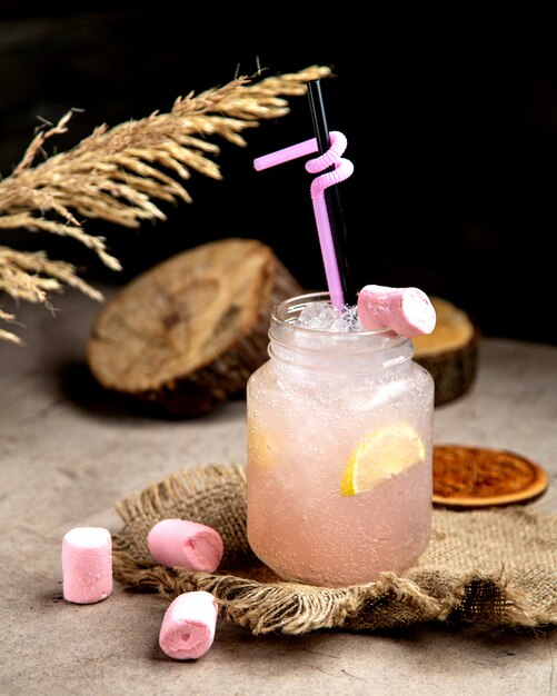 Boisson gazeuse rose clair avec une tranche de citron garnie de marshmellow