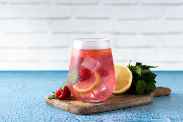 Boisson de limonade aux framboises en verre sur fond bleu