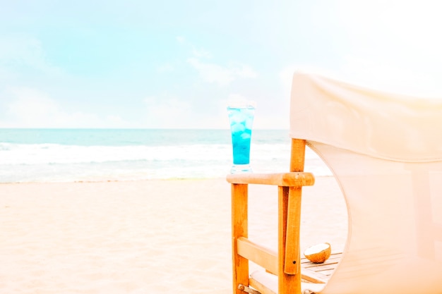 Boisson lumineuse bleue sur le bras de la chaise en bois et noix de coco