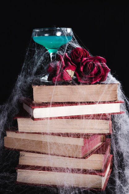 Boisson verte avec des roses, des livres et une toile d'araignée