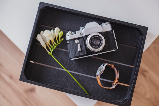 Photo gratuite boîte en bois avec caméra, montre et fleur