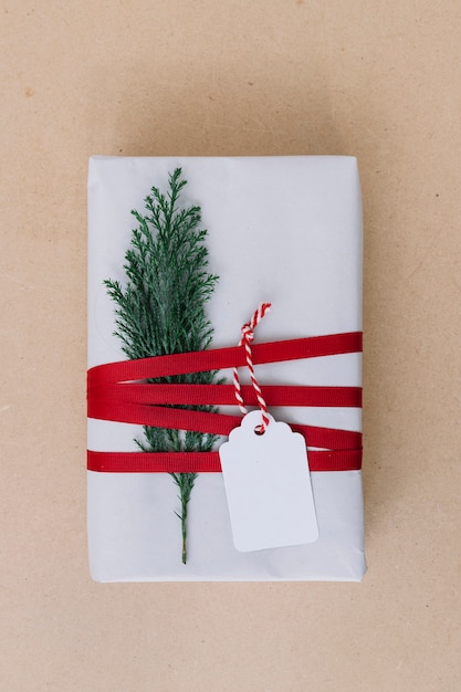 Photo gratuite boîte cadeau blanche avec branche de cyprès sur table