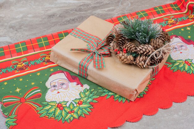 Boîte-cadeau de Noël et guirlande avec pomme de pin sur marbre.