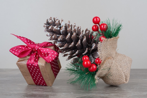 Boîte-cadeau de Noël et pomme de pin sur table en marbre.