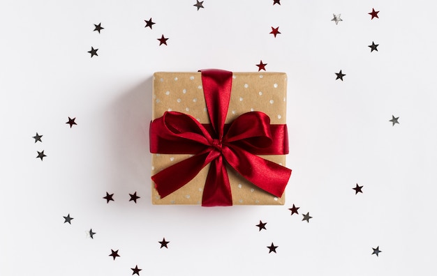 Boîte de cadeau de vacances de Noël arc rouge sur la table de fête décorée avec étoiles scintillantes