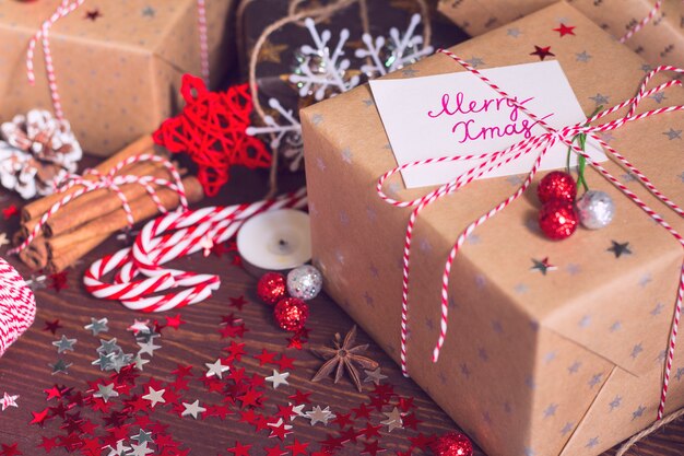 Boîte de cadeau de vacances de Noël avec carte postale joyeux Noël sur la table de fête décorée avec des pommes de pin cannelle