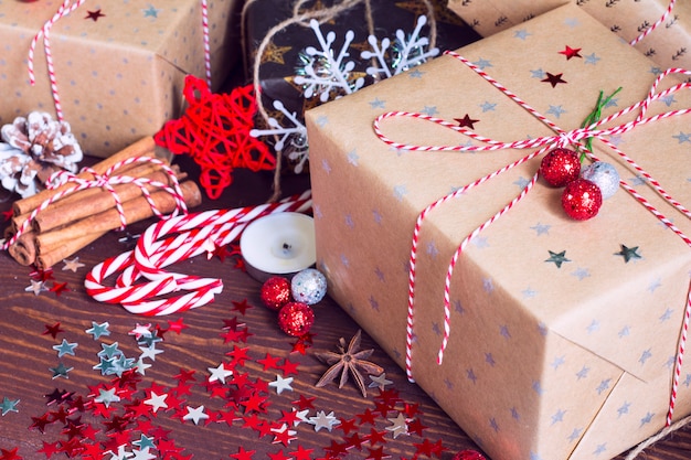 Boîte de cadeau de vacances de Noël sur la table de fête décorée avec des pommes de pin cannelle noix de canne de bonbon et des étoiles scintillent sur fond en bois