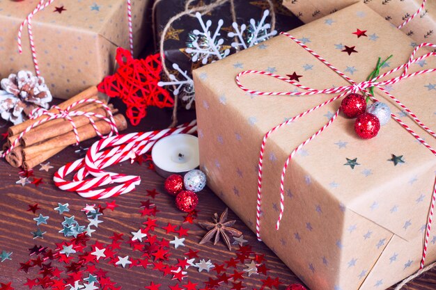 Boîte de cadeau de vacances de Noël sur la table de fête décorée avec des pommes de pin cannelle noix de canne de bonbon et des étoiles scintillent sur fond en bois