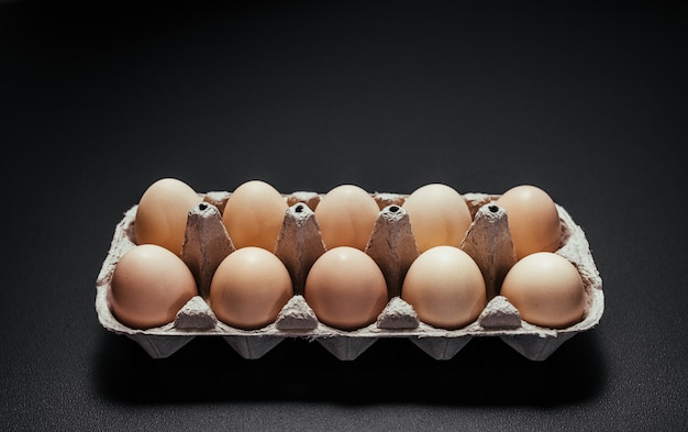 Boîte à oeufs en carton sur un fond en bois noir.