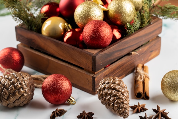 Une boîte d'ornements d'arbre de Noël rouge et doré sur la table.