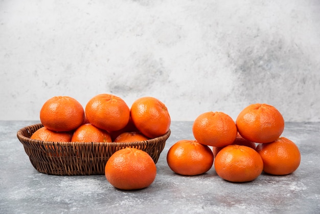 Une boîte en osier pleine de fruits orange juteux sur table en pierre.