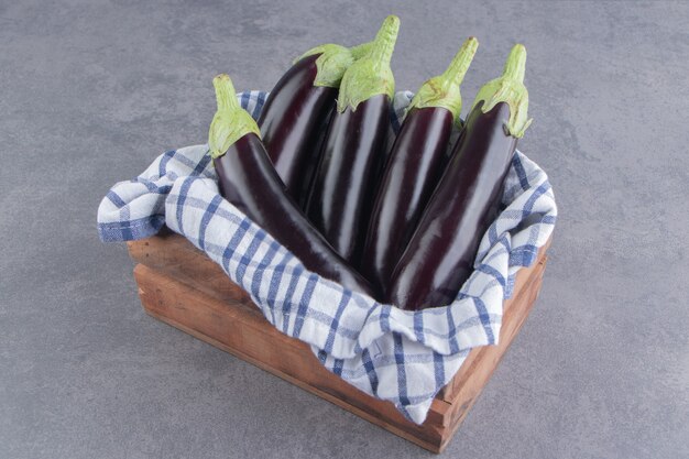 Une boîte pleine d'aubergines sur la surface en marbre