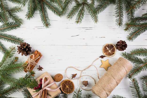 Boîte présente dans un emballage de Noël près de la canette de fils entre des branches de sapin