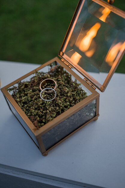Boîte en verre avec des anneaux de mariage sur la table blanche