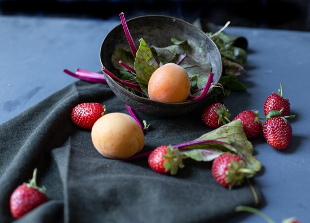 Bol avec des abricots et des épinards à l'intérieur et des fraises à l'extérieur.