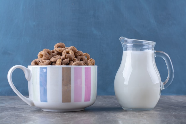 Photo gratuite un bol d'anneaux de céréales au chocolat sain avec un pot de lait en verre.