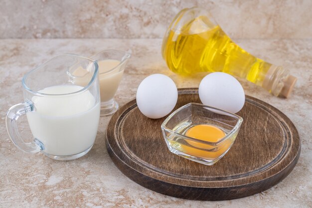 Un bol en argile de fromage cottage avec du lait et une bouteille en verre d'huile