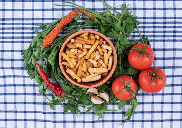 Photo gratuite un bol d'argile de gressins avec des légumes sur une nappe