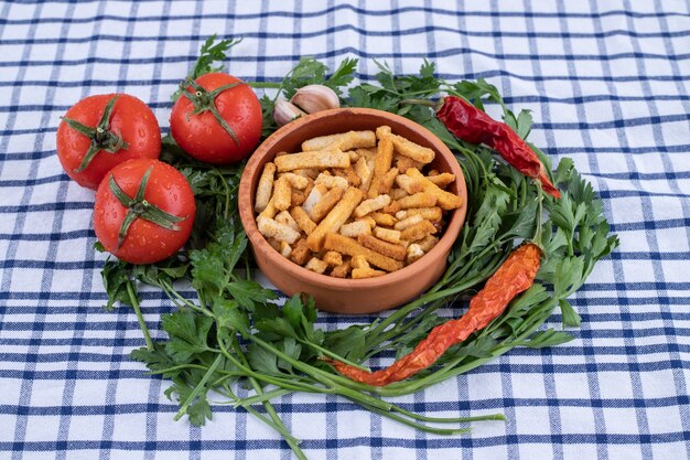 Un bol d'argile de gressins avec des légumes sur une nappe