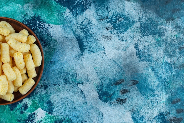 Un bol de bâtonnets de maïs sucré , sur la table bleue.