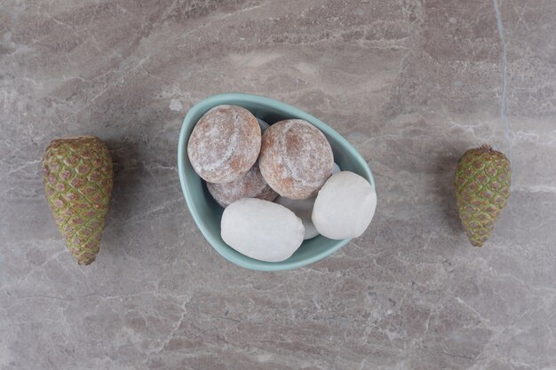 Un bol de biscuits à côté de pommes de pin sur marbre