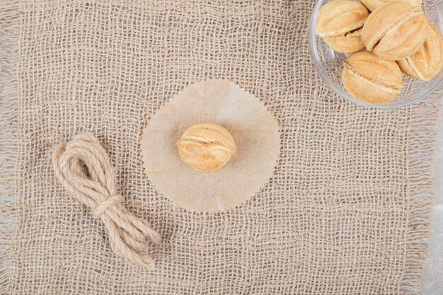 Bol de biscuits en forme de noix dans un bol en verre sur toile de jute. Photo de haute qualité