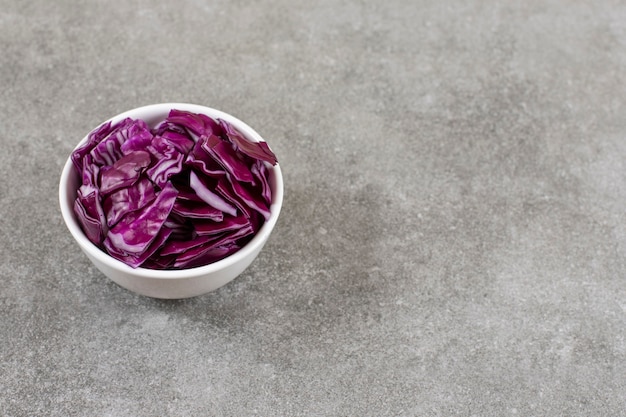 Bol blanc de chou violet haché sur table en pierre.