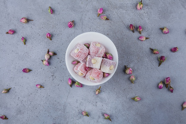 Photo gratuite bol blanc de délices de rose avec des noix sur la surface de la pierre.