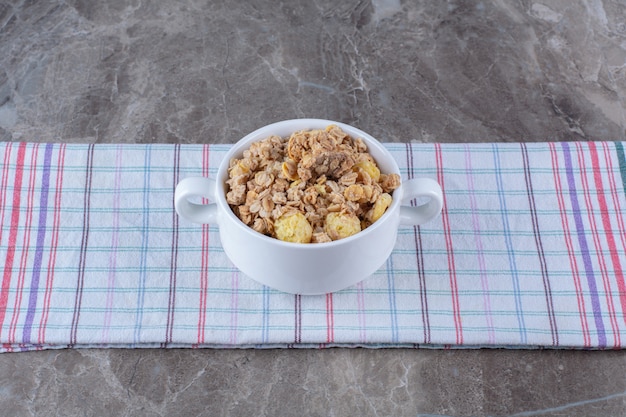 Un bol blanc plein de délicieux cornflakes sains sur nappe.